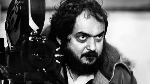 Imagem do stanley kubrick com uma câmera de cinema antiga.
